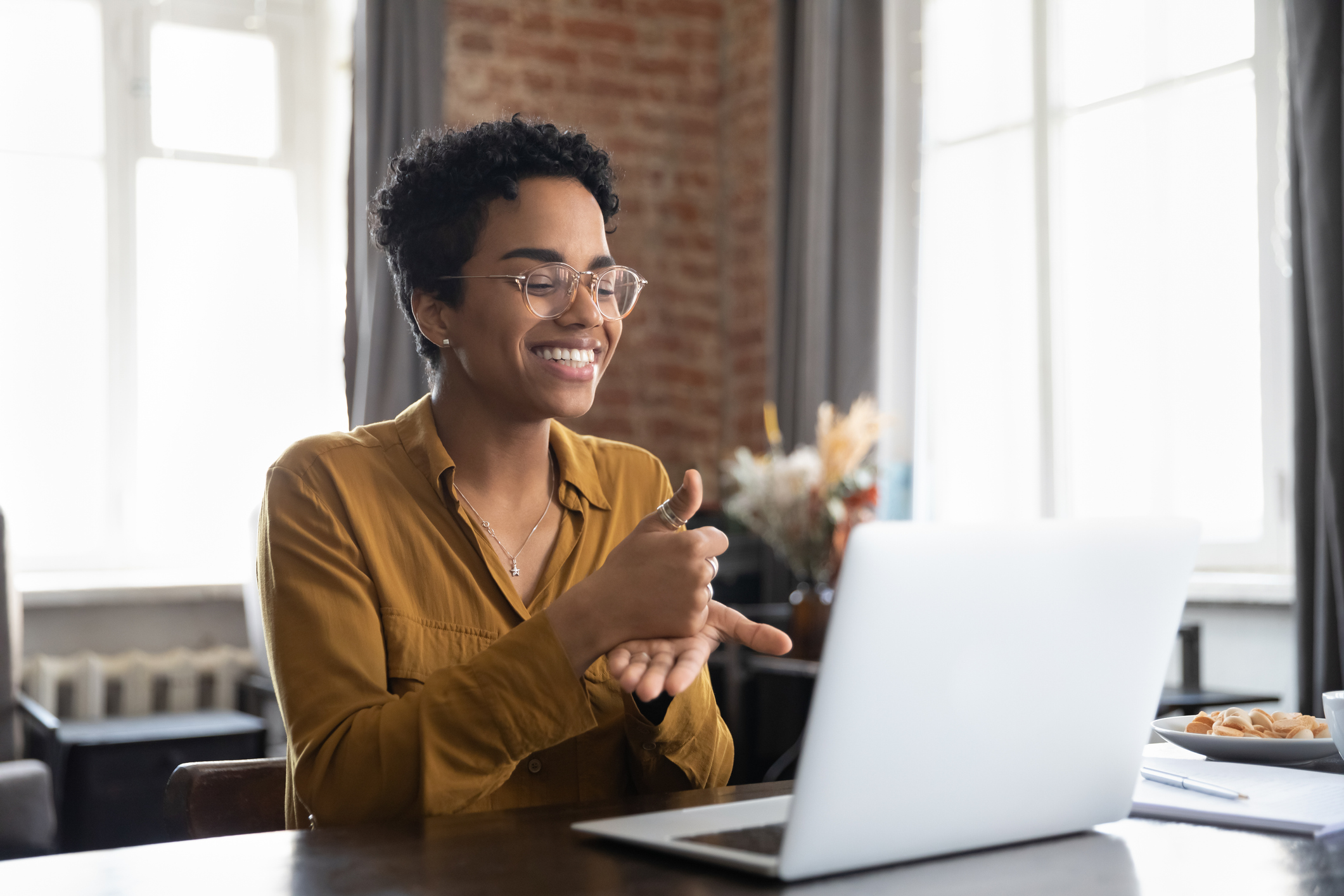 Therapist in glasses talking on video call, using sign language, speaking to patient with hearing disability, deafness, showing gestures at screen