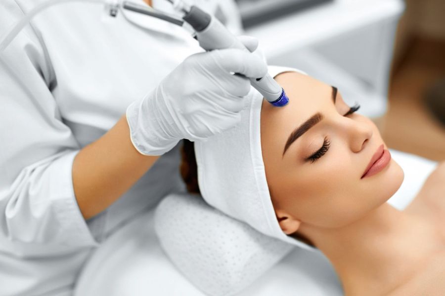 The cosmetologist makes the procedure Microdermabrasion of the facial skin of a beautiful, young woman in a beauty salon.Cosmetology and professional skin care.