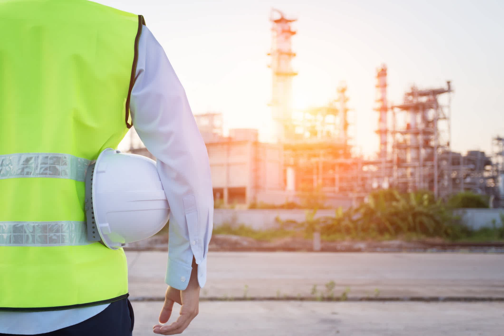 Engineering man standing with white safety helmet near to oil refinery. | Watermark
