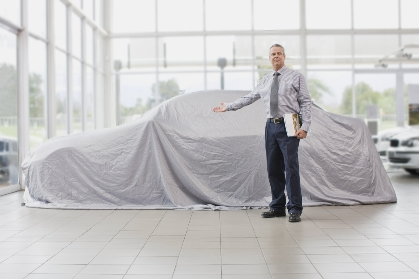 Car salesman displaying car under cloth