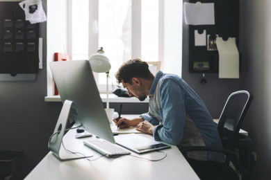 Modern designer sitting in front of computer and working in office