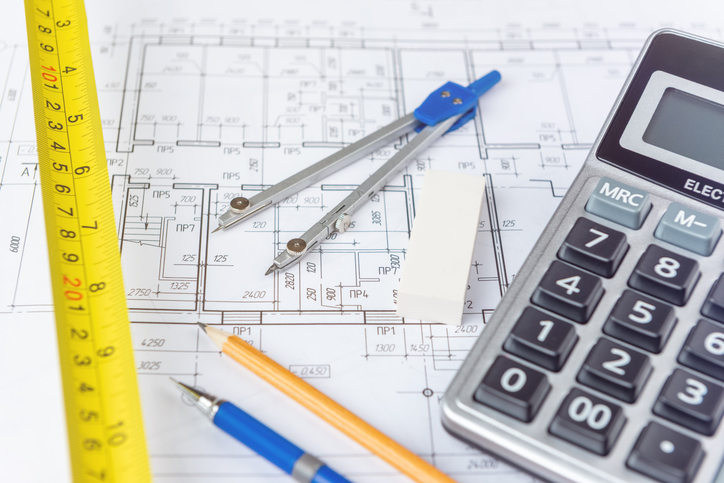 Photo of a blueprint and a calculator on a desk.