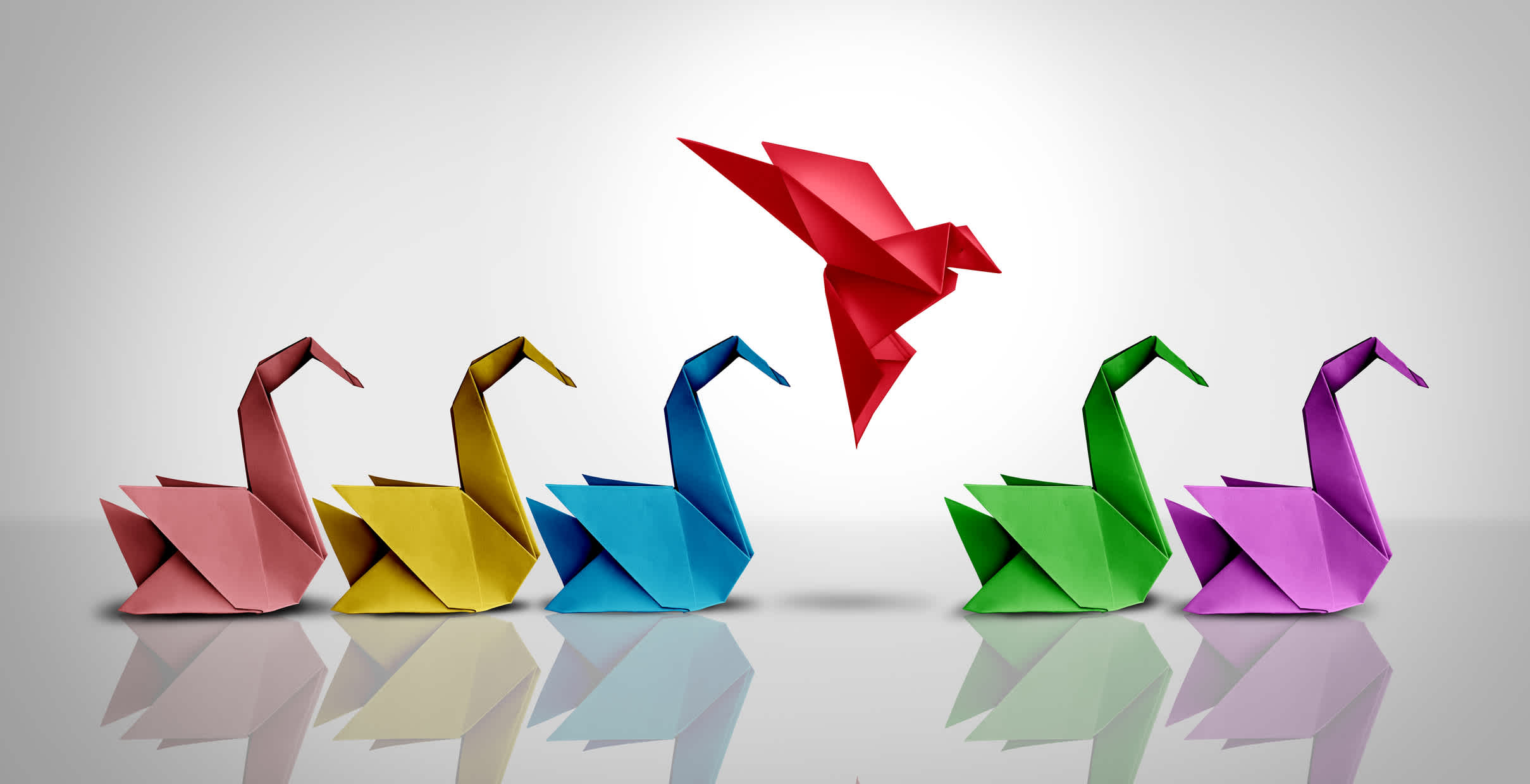 Innovative thinker concept and new idea thinking as a symbol of revolutionary innovation and inspiration metaphor as a group of paper swans and a game changer origami bird in flight. | Watermark