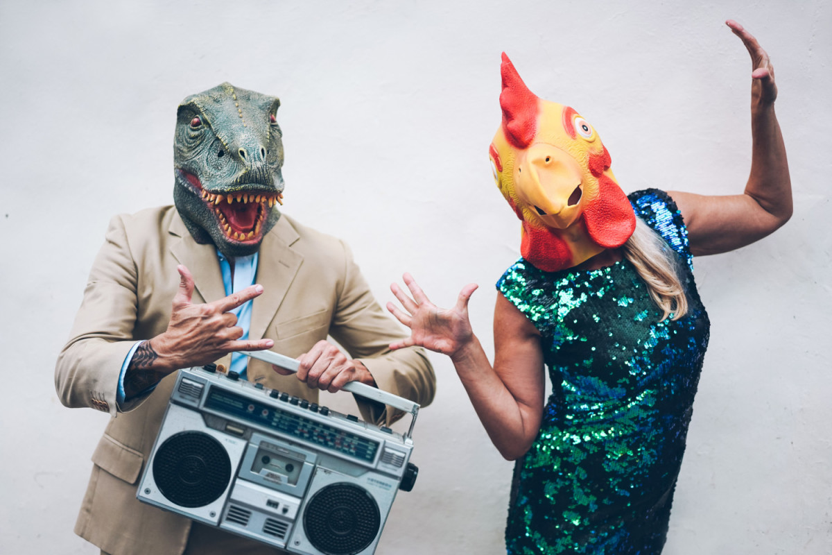 Crazy senior couple dancing for new year's eve party wearing t-rex and chicken mask