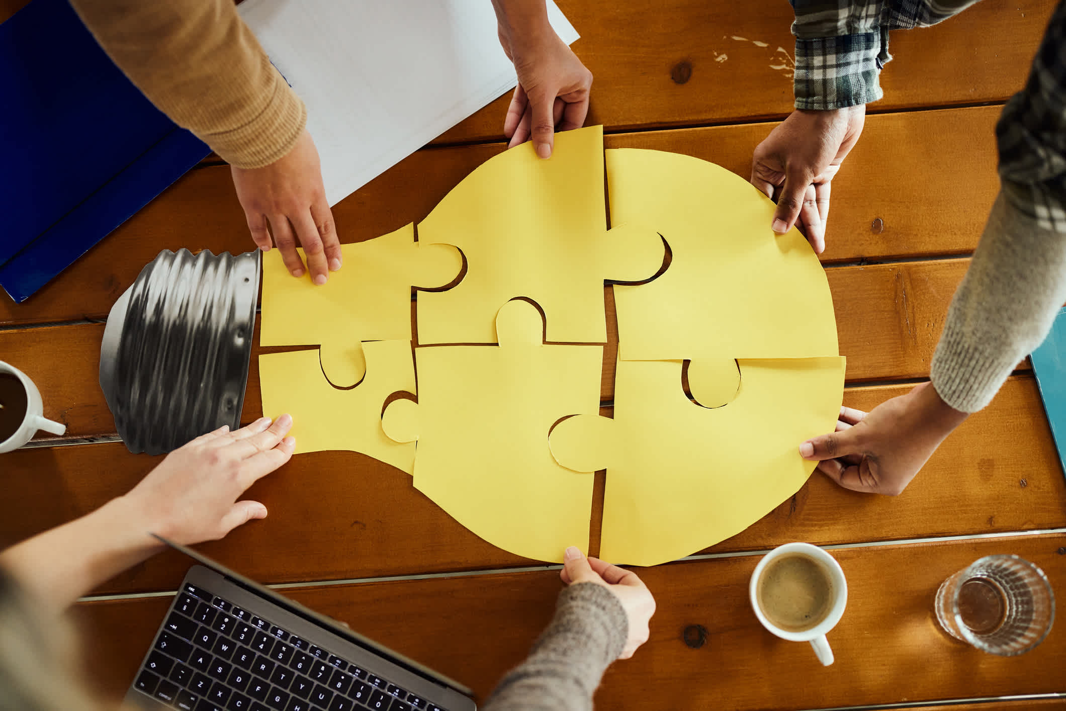Above view of unrecognizable creative team cooperation while making a light bulb of puzzles at a casual office. | Watermark