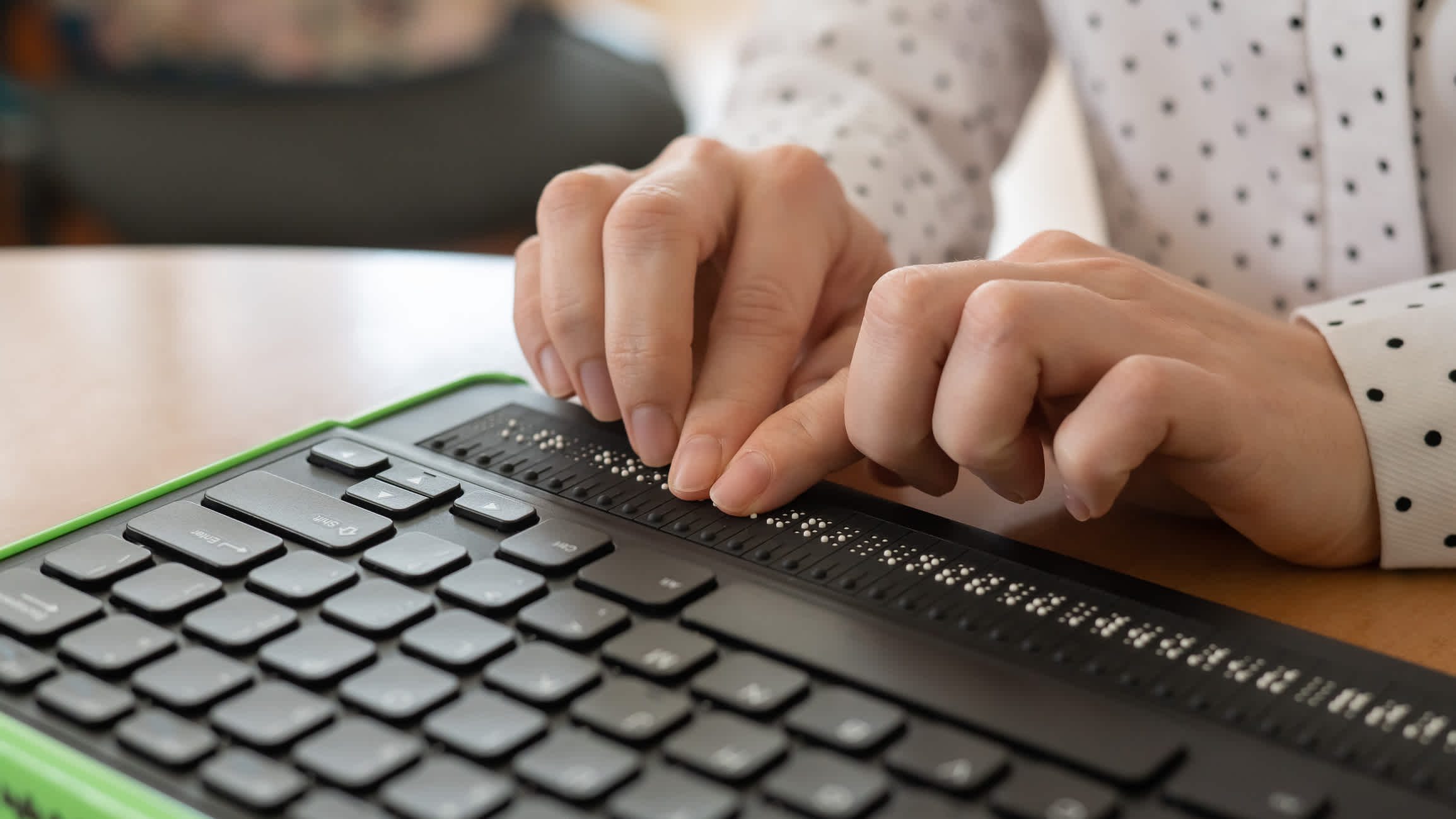 A blind person uses a computer with a Braille display and a computer keyboard