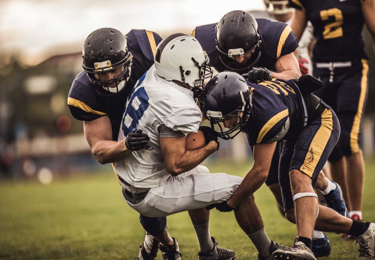 American football players tackling opposite's team quarterback during the match.