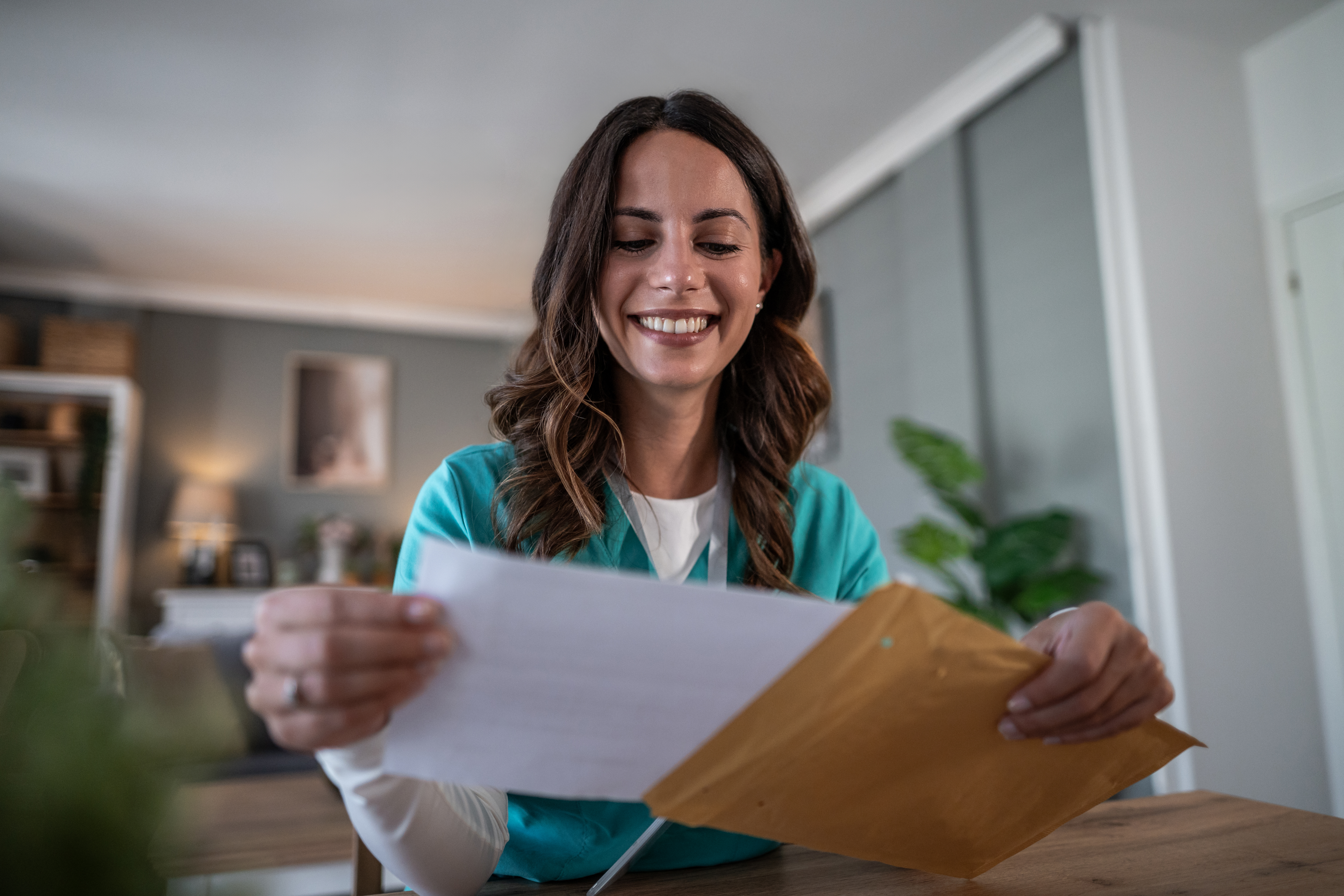 Smiling professional opening a direct mail envelope at her desk