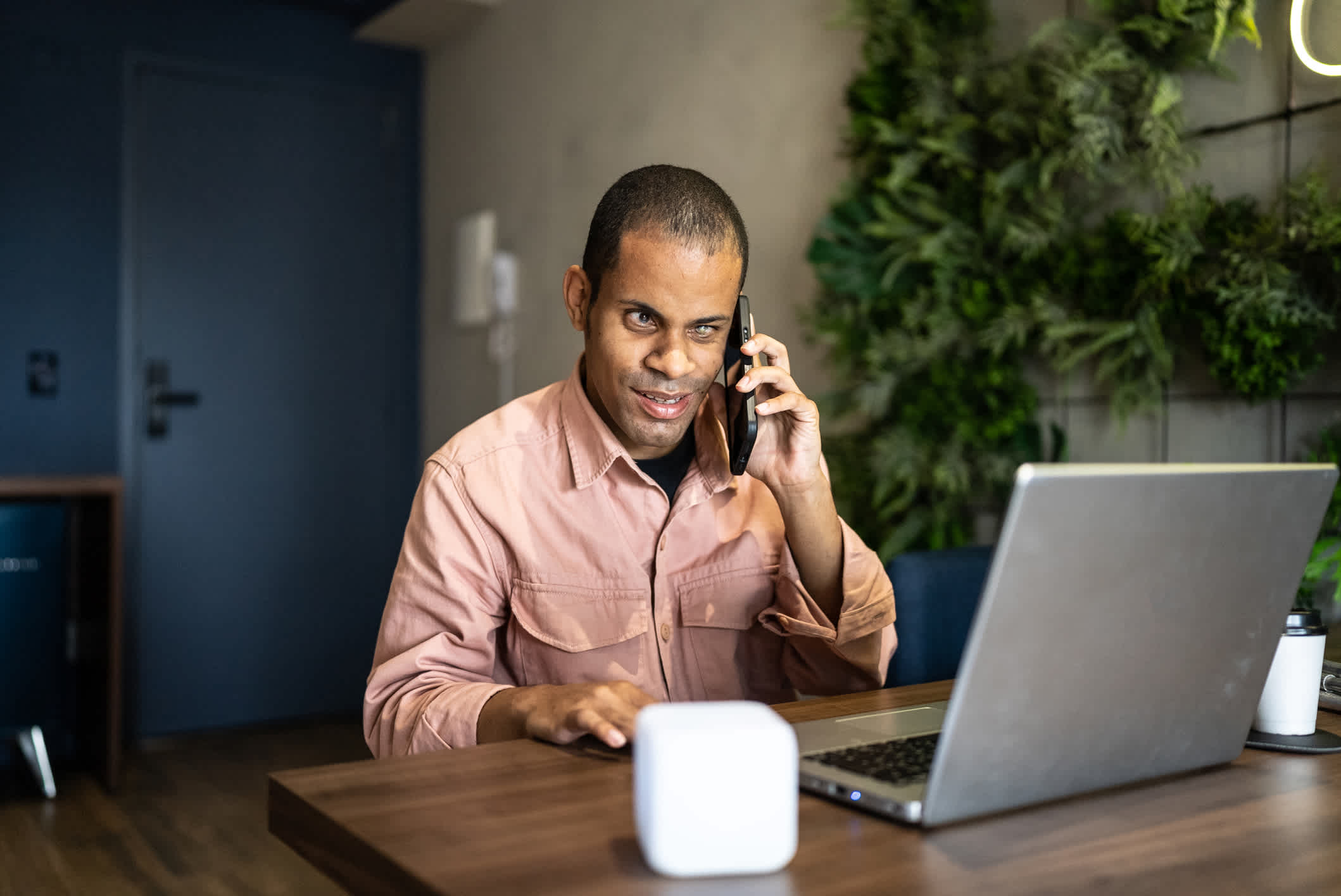 Visually impaired man talking on the mobile phone and using laptop in the office