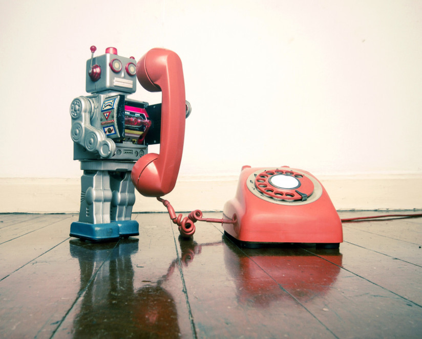 big silver robot toy on the phone standing on an old wooden floor