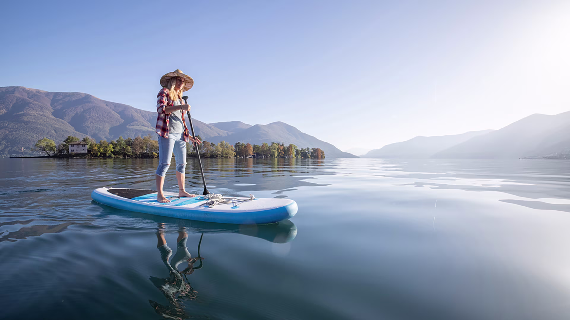 Frau beim Stand-up-Paddling auf einem See für ein gesundes Ganzkörpertraining