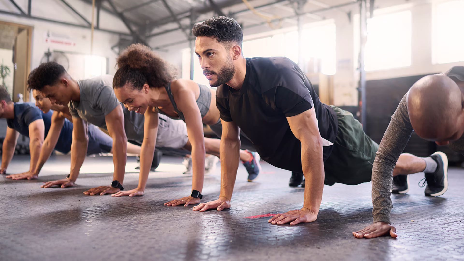Männer und Frauen machen gemeinsam Planks im Fitnessstudio