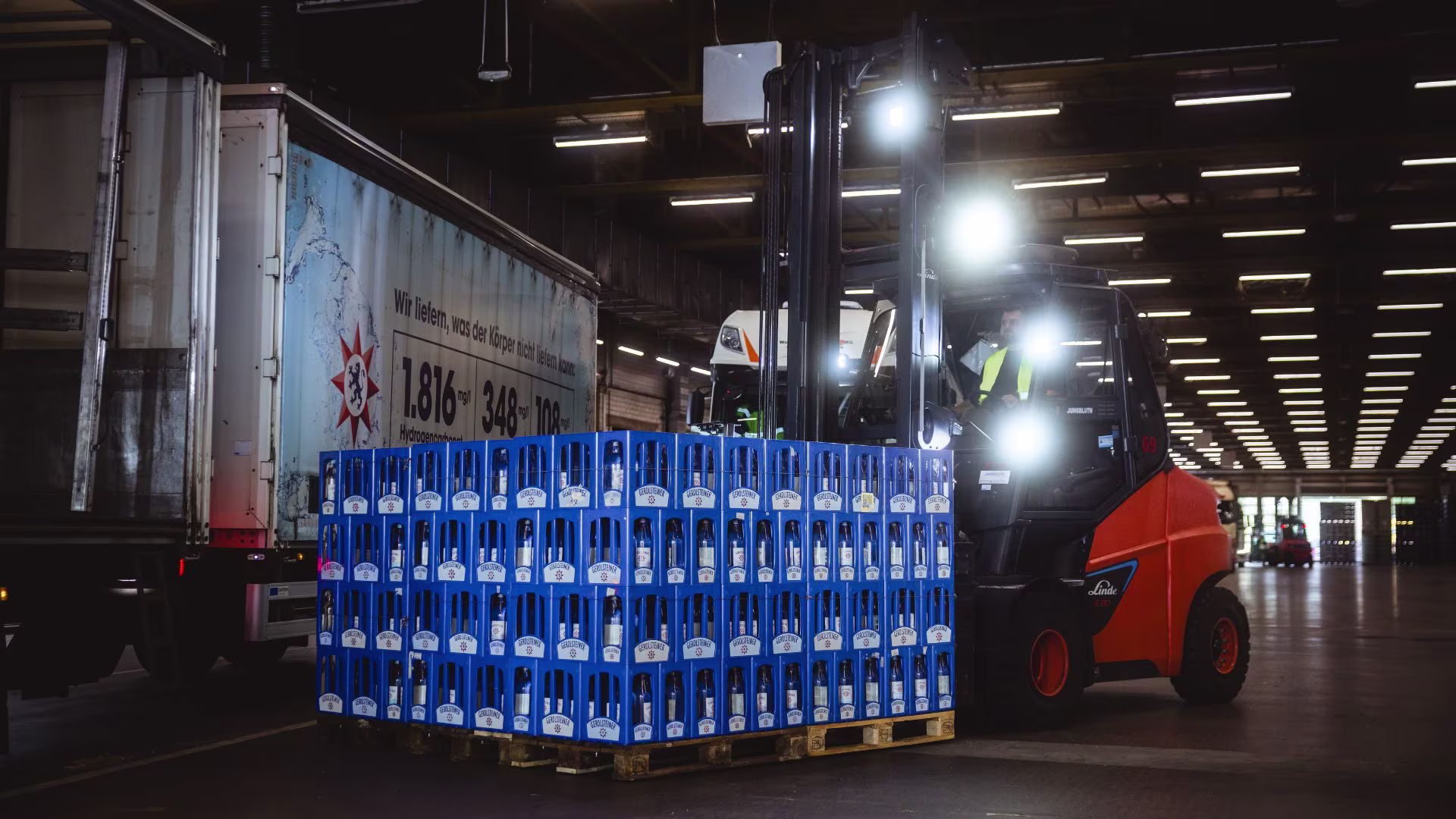 Gabelstapler transportiert eine Palette mit Mineralwasserkästen in einer modernen Lager- und Logistikhalle.