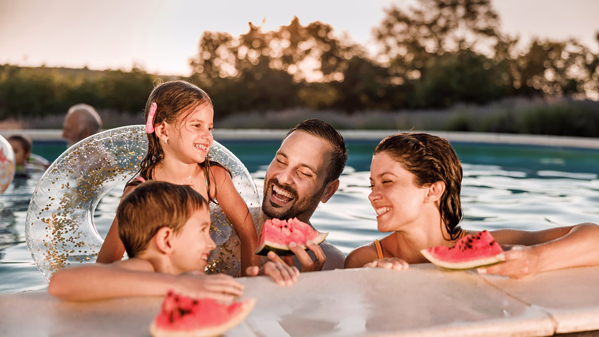 Familie isst Wassermelone im Pool. 