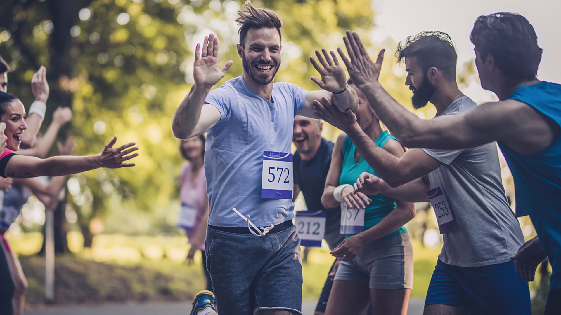 Glücklicher Halbmarathon-Läufer klatscht sich mit Publikum ab.