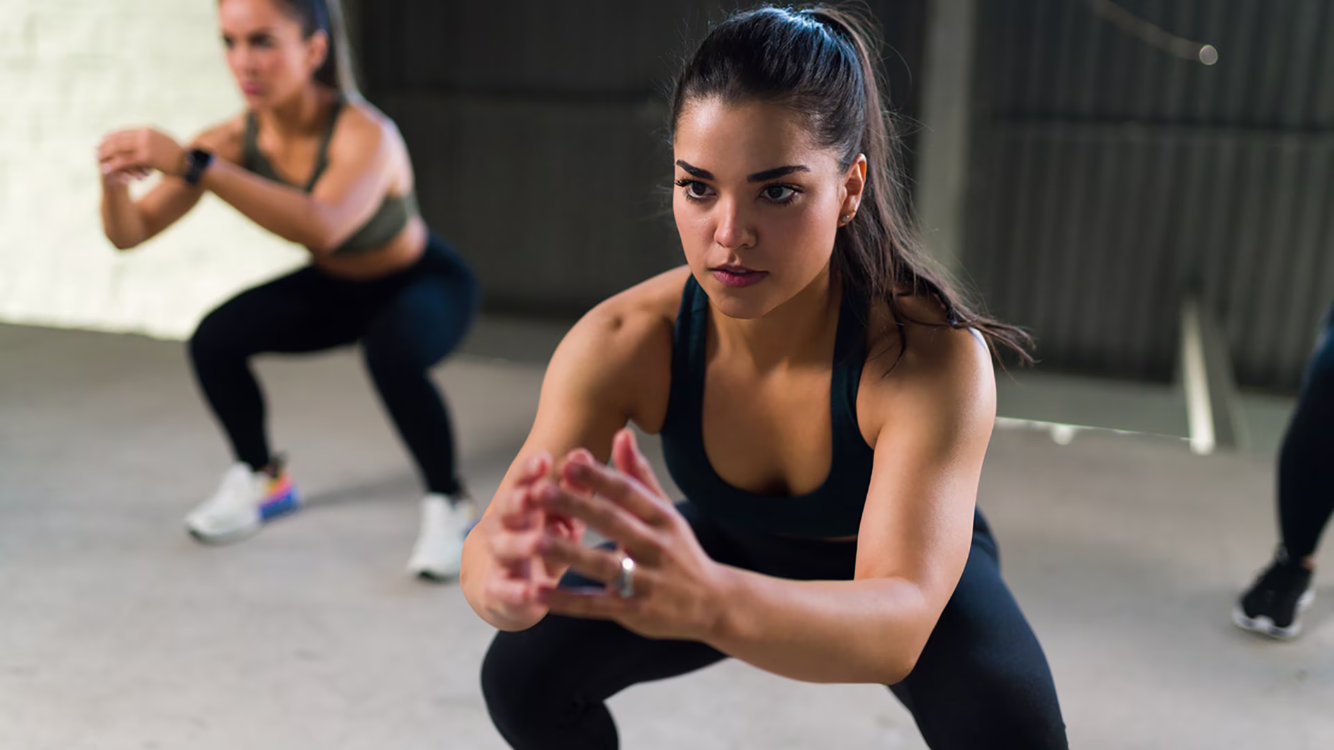 Zwei Frauen beim Intervalltraining mit Kniebeugen im Fitnessstudio