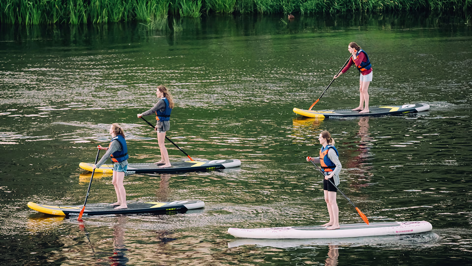 Junge Menschen mit der richtigen SUP-Ausrüstung beim Stand-up-Paddling auf einem Fluss