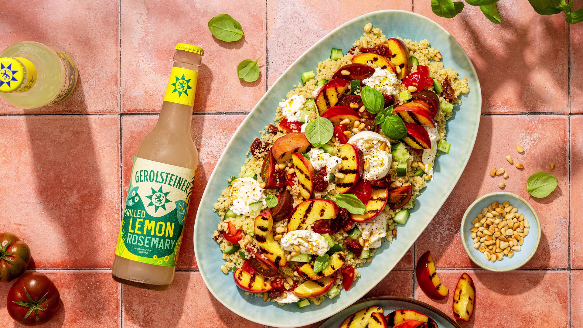 Farbenfroher Couscoussalat mit gegrillten Nektarinen, cremiger Burrata, frischen Kräutern und gerösteten Pinienkernen. Ergänzt wird das sommerliche Gericht durch eine Gerolsteiner Grilled Lemon Rosemary Limonade.