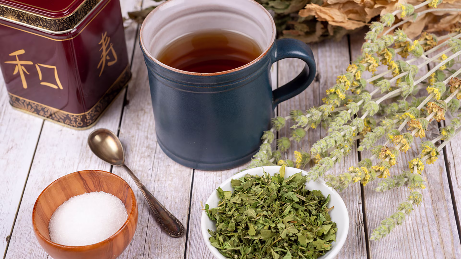 Grüner Tee in Tasse mit Zucker, Lavendel und getrockneten Kräutern.