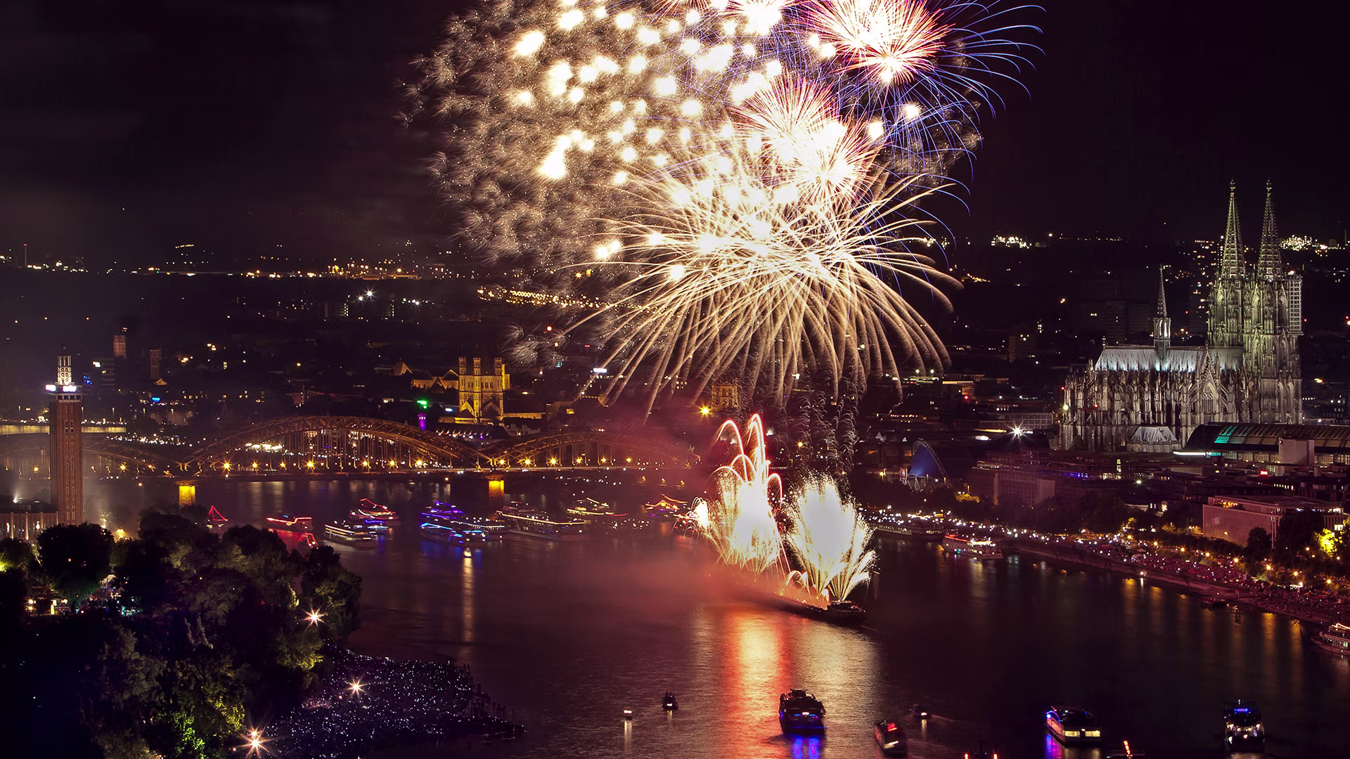 Beeindruckendes Feuerwerk über dem Rhein vor der Kulisse des Kölner Doms. Die bunten Lichter spiegeln sich im Wasser und schaffen eine einzigartige, festliche Atmosphäre.