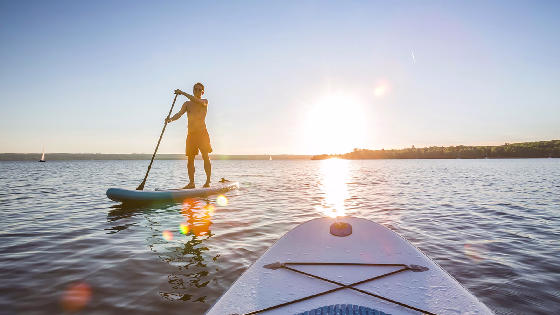 SUP-Anfänger beim Stand-up-Paddling auf dem Meer bei Sonnenuntergang