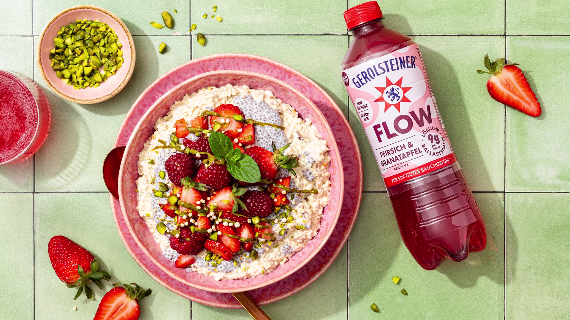 Eine Schale Haferflocken und Chia-Pudding wird mit frischen Erdbeeren, Himbeeren und Pistazien garniert. Dazu sorgt Gerolsteiner Flow Pfirsich & Granatapfel für eine fruchtige Begleitung zum Frühstück.
