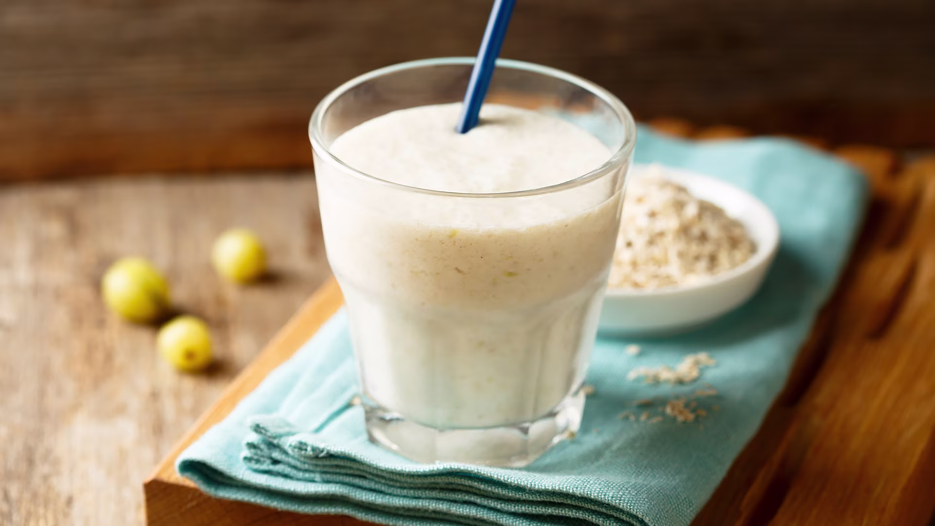 Reisprotein-Vanille-Shake in einem Glas mit Strohhalm auf einem Holztisch.