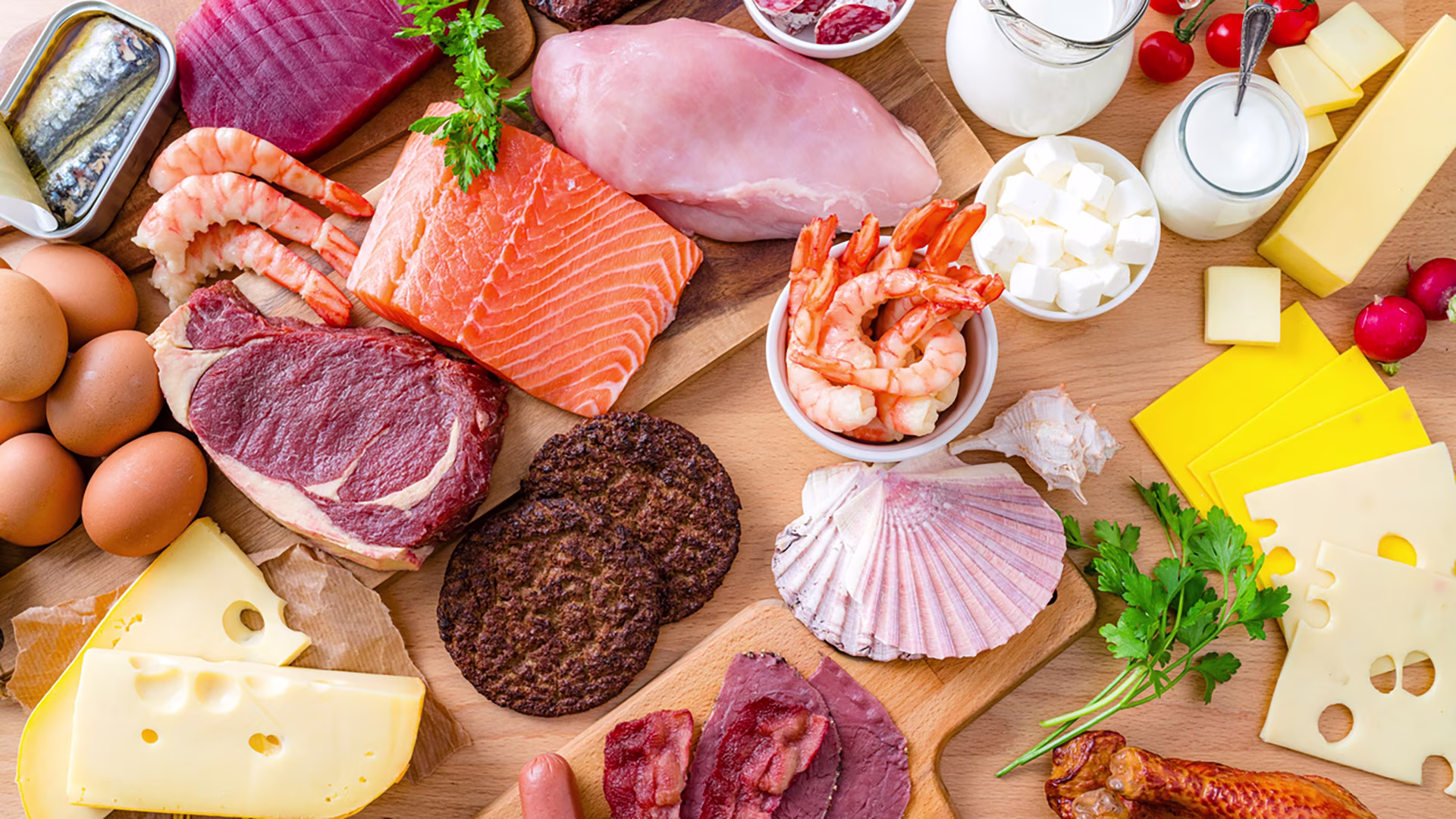 Verschiedene proteinreiche tierische Lebensmittel, die auf Holzbrettchen auf einem Tisch liegen