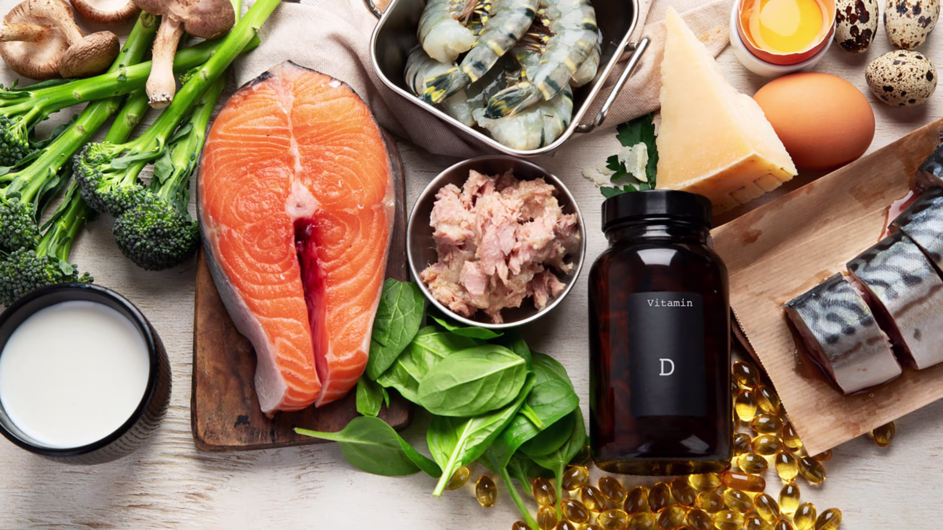 Vitamin-D-reiche Lebensmittel wie Champignons, Lachs, Thunfisch, Käse sowie Eier liegen nebeneinander auf einer Tischfläche