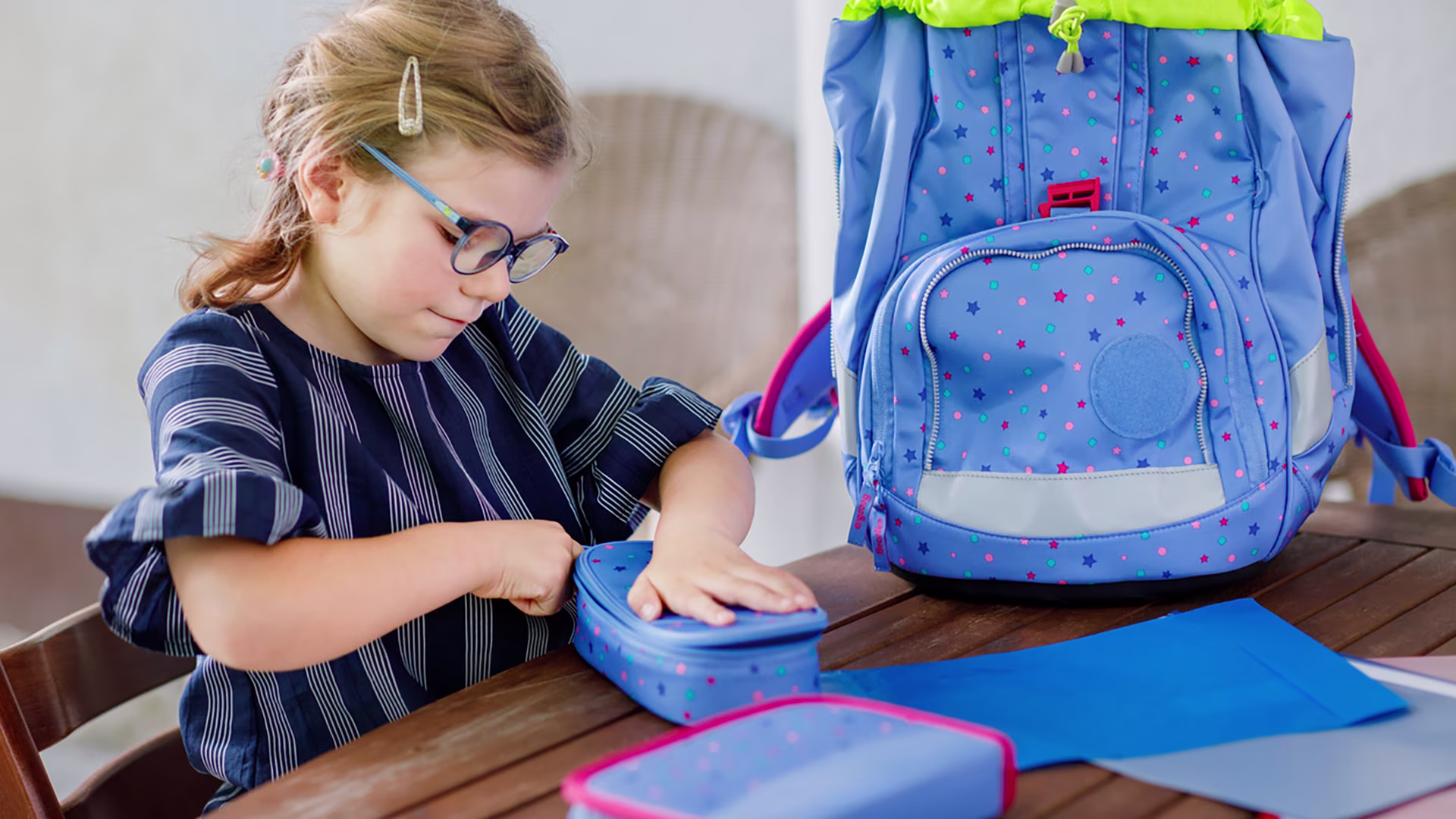 Mädchen ist dabei ihren Schulranzen zu packen und schließt gerade ihr Etui.