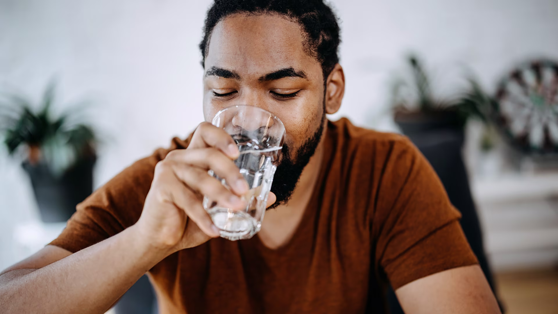 Ein Mann trinkt Mineralwasser aus einem Glas.