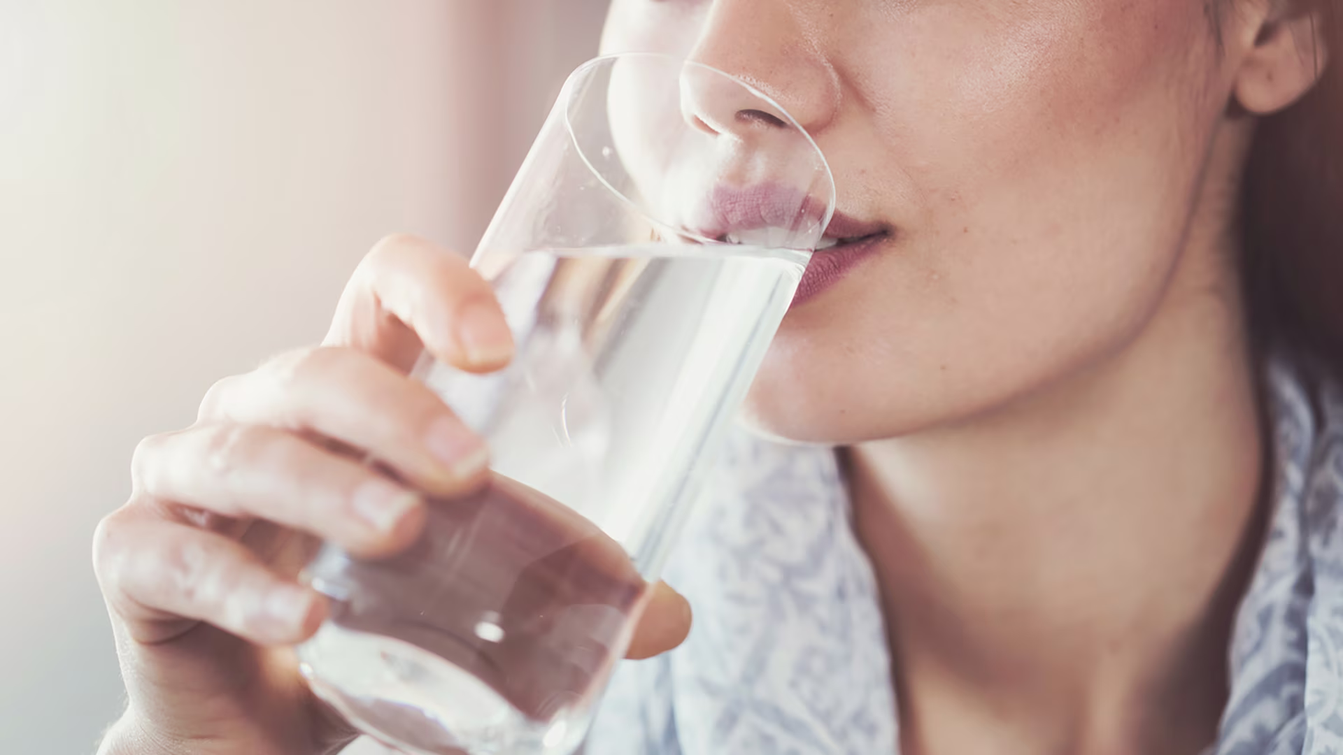Junge Frau stillt ihren Durst mit einem Glas Wasser