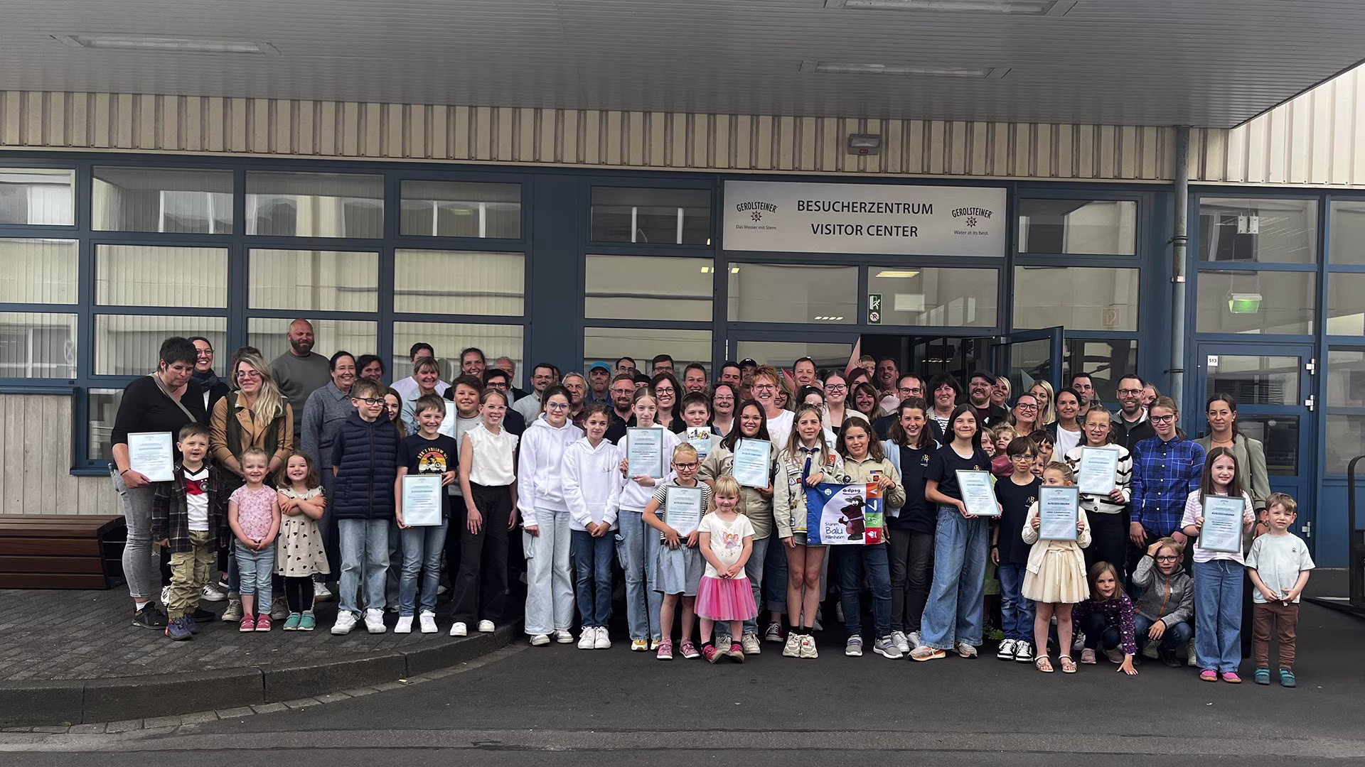 Gruppenfoto zahlreicher Kinder, Jugendlicher und Erwachsener vor dem Gerolsteiner Besucherzentrum – viele halten stolz Urkunden in den Händen, anlässlich der Auszeichnung ‚Team mit Stern 2025‘.