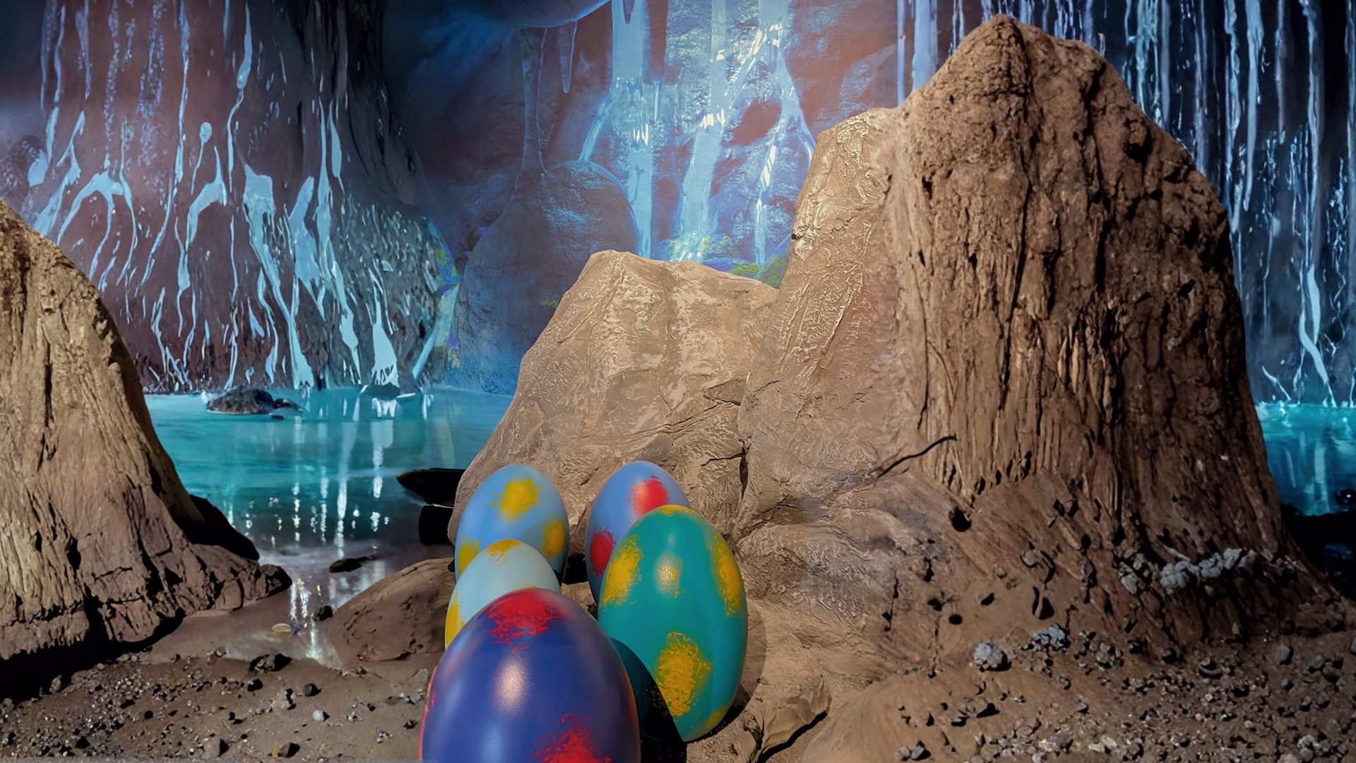 Inszenierte Höhlenlandschaft mit Felsen, Baumstümpfen und bunten Dinosaurier-Eiern vor einer leuchtenden Unterwasser- oder Fantasiekulisse.