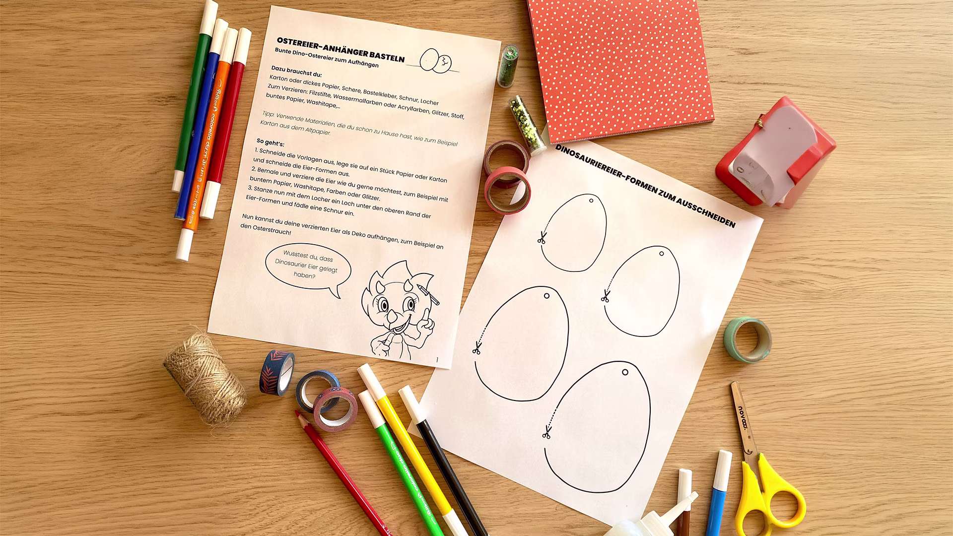Eine Bastelvorlage für Ostereier-Anhänger liegt auf einem Tisch, umgeben von Stiften, Schere, Klebeband und Bastelmaterial. Die Vorlage lädt dazu ein, kreative Dino-Ostereier auszuschneiden, zu bemalen und als frühlingshafte Dekoration aufzuhängen.