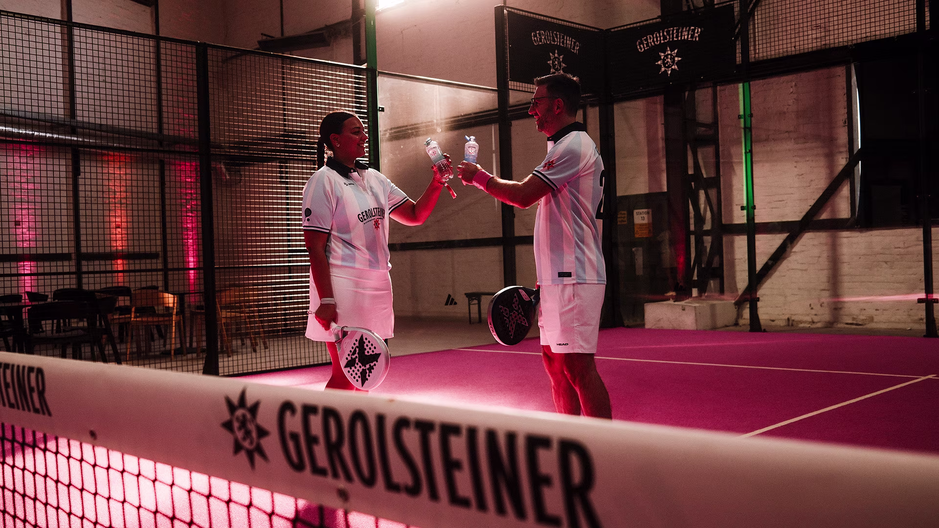 Zwei Padel-Spieler stoßen nach dem Spiel mit Gerolsteiner Getränken an.