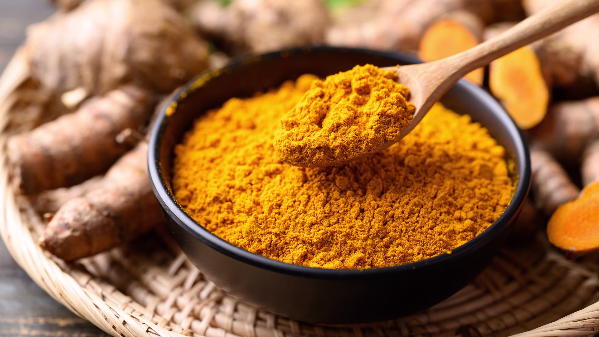 Schale mit Kurkumapulver und frische Kurkuma-Knolle