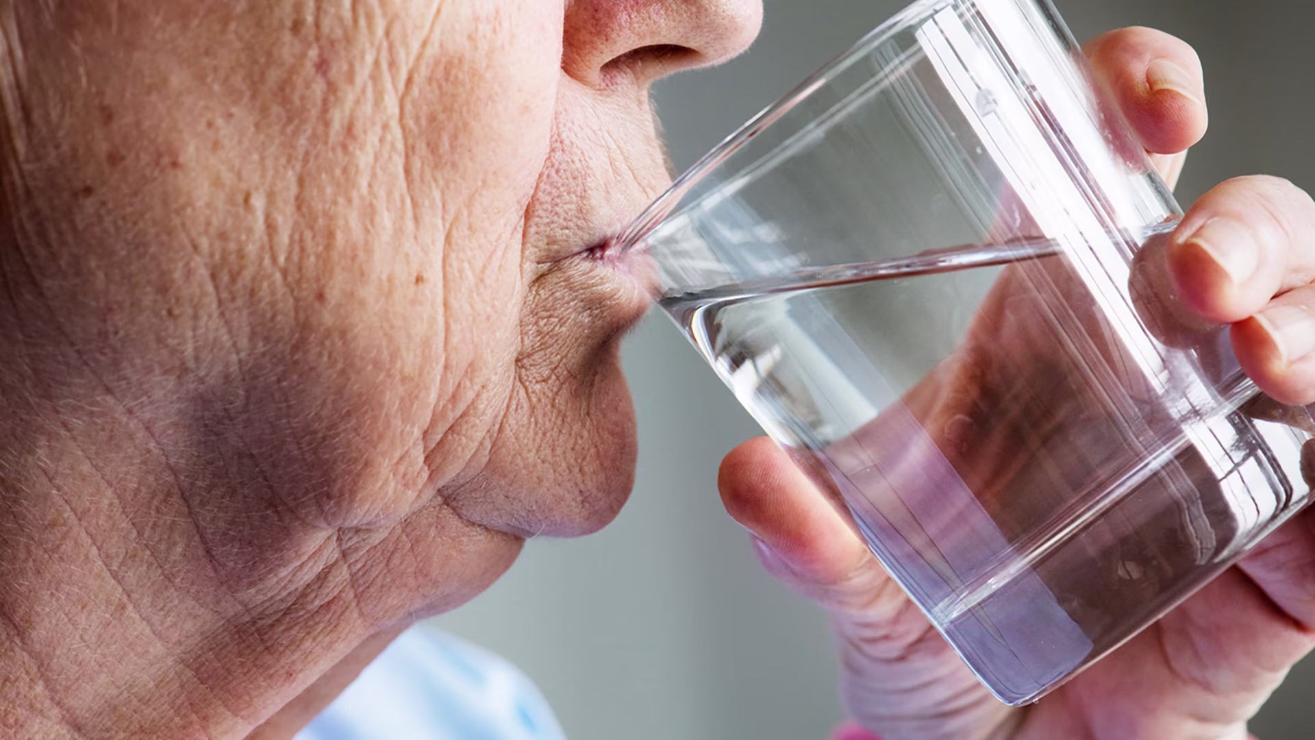 Seniorin trinkt Wasser zur Vorbeugung von Flüssigkeitsmangel im Alter