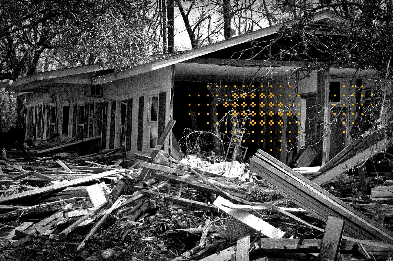 black and white photo of a home that was destroyed by a hurricane with debris and trees surrounding the home