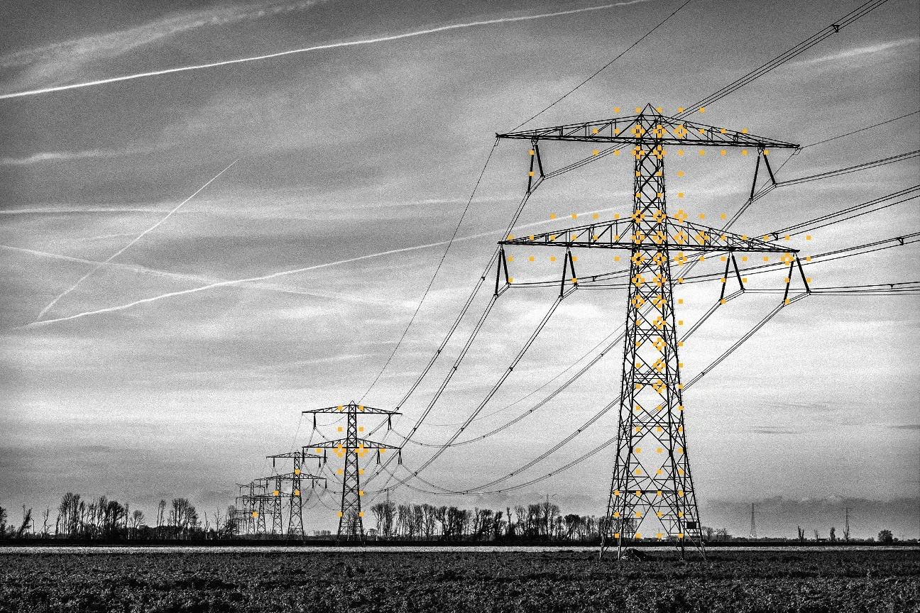 black and white photo of power lines over a field with yellow glyphs on the transmission tower