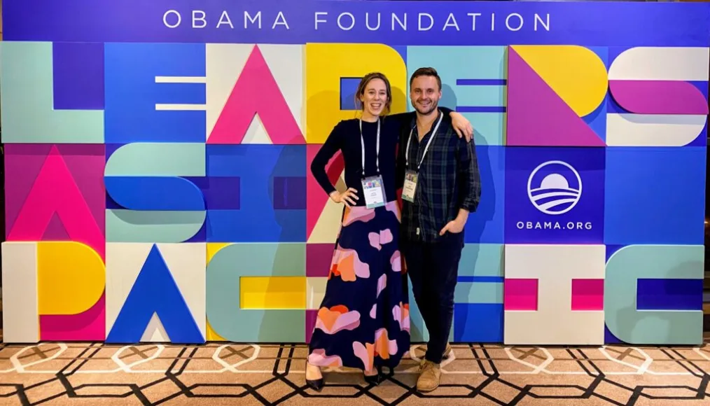 Skye and Tim smile in front of a colorful background at the Leaders: Asia-Pacific convening, 2019.