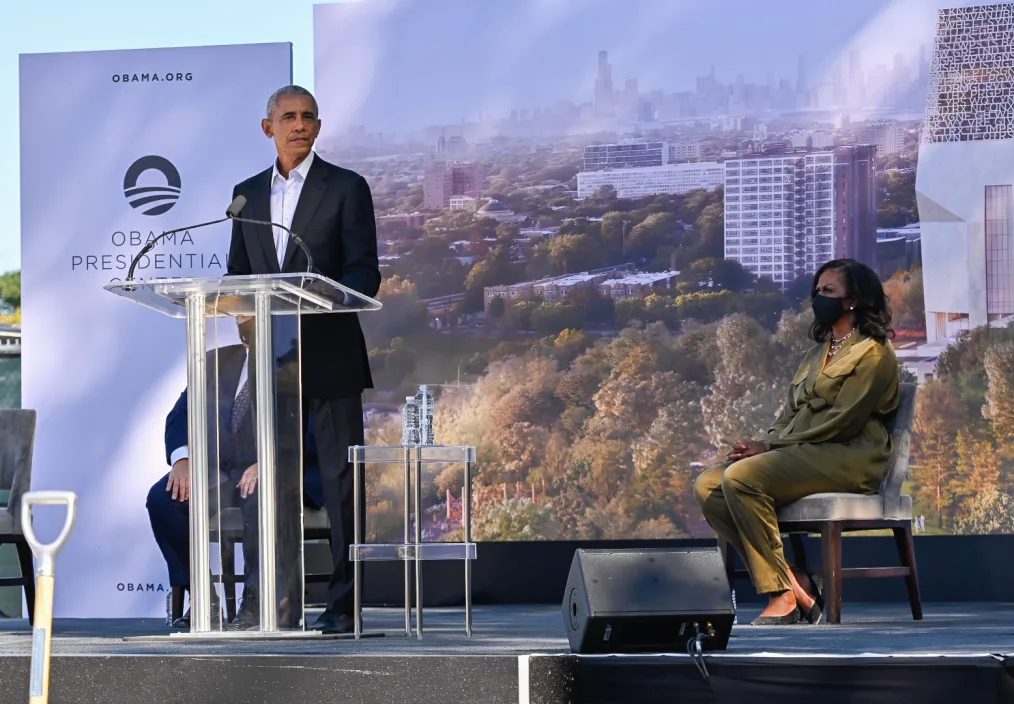 President Obama delivers remarks from behind a podium, with Obama Presidential Center images behind him.