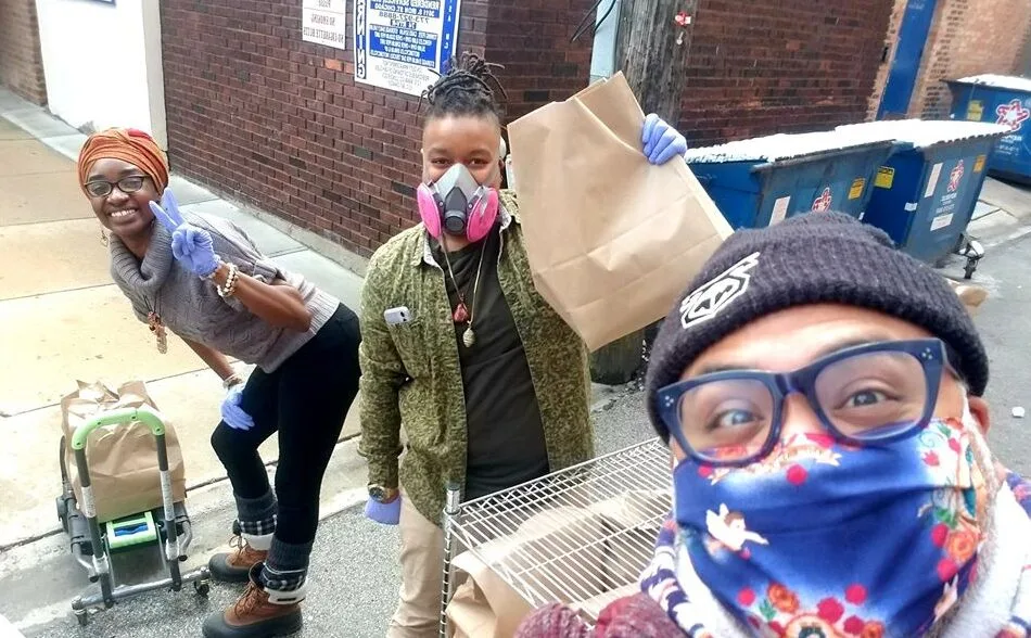 Three people pose for a selfie while delivering food packages.