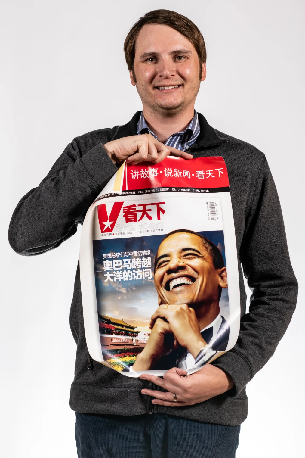 Jordan Oster smiles to camera holding an Obama campaign poster from China.
