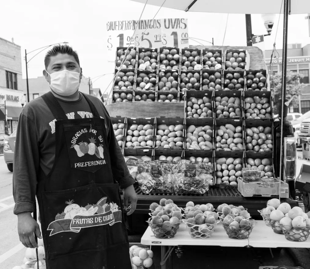 A street vendor stands next to his fruit stand