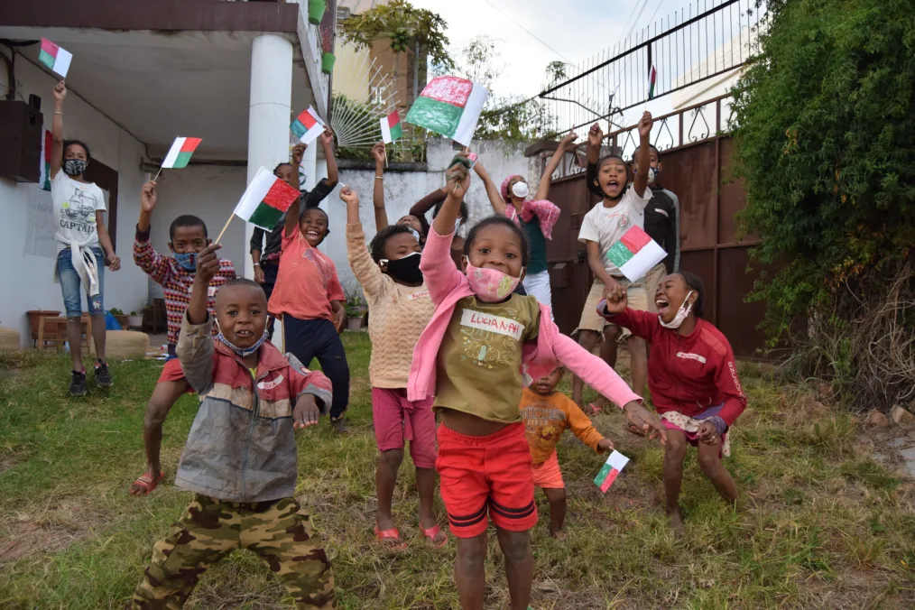 A group of happy young children hold up the Madagascar flag