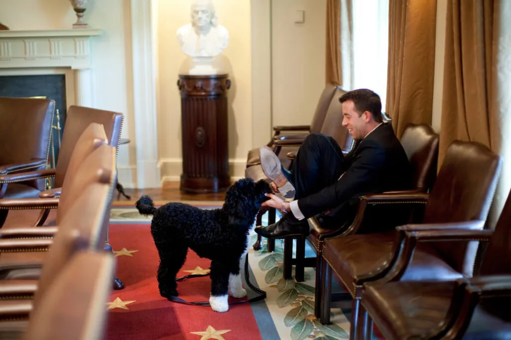 White House Deputy Director of Oval Office Operations Brian Mosteller attempts to protect his shoes as he plays with the Obama family dog "Bo"