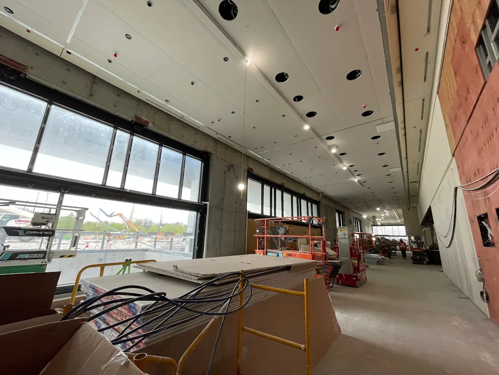 An image of the construction of the Hadiya Pendleton Atrium located in the Forum Building on the Obama Presidential Center campus. The picture features the long windows that will be featured in the Atrium. On the ceiling are white panels with lights.