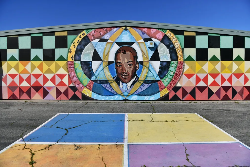 A mural of Martin Luther King, Jr. from a playground. The mural features his face and colorful patterns in yellow, blue, red, orange, and black. 