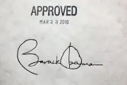 The image is a photograph of Barack Obama’s signature signed on the Affordable Care Act. The image is of a sheet of paper: at the top of the paper is the word “Approved” stamped on. Underneath “Approved” is text that reads, “March 23 2010.” Below that is President Barack Obama’s signature. 